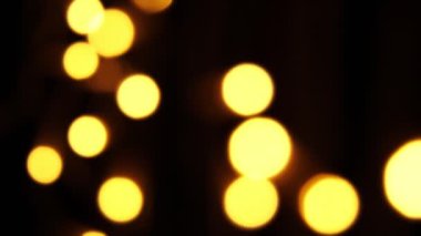 Soyut sahte arkaplan hareket halinde. Parlak, bulanık altın parçacıklar, ışıklar. Koyu arkaplandaki çelenklerden parlak bir bokeh. Yeni yıl ya da Noel arkaplanı.
