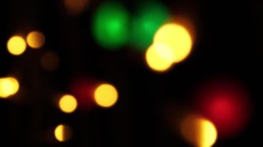 Soyut sahte arkaplan hareket halinde. Parlak, bulanık renkli parçacıklar, ışıklar. Koyu arkaplandaki çelenklerden parlak bir bokeh. Yeni yıl ya da Noel arkaplanı.