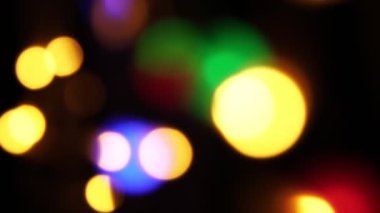 Soyut sahte arkaplan hareket halinde. Parlak, bulanık renkli parçacıklar, ışıklar. Koyu arkaplandaki çelenklerden parlak bir bokeh. Yeni yıl ya da Noel arkaplanı.