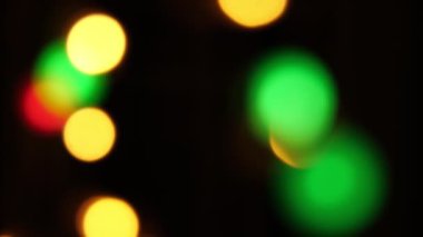 Soyut sahte arkaplan hareket halinde. Parlak, bulanık renkli parçacıklar, ışıklar. Koyu arkaplandaki çelenklerden parlak bir bokeh. Yeni yıl ya da Noel arkaplanı.