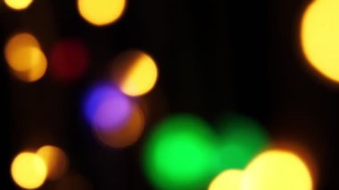 Soyut sahte arkaplan hareket halinde. Parlak, bulanık renkli parçacıklar, ışıklar. Koyu arkaplandaki çelenklerden parlak bir bokeh. Yeni yıl ya da Noel arkaplanı.