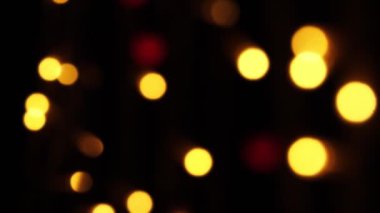 Soyut sahte arkaplan hareket halinde. Parlak, bulanık renkli parçacıklar, ışıklar. Koyu arkaplandaki çelenklerden parlak bir bokeh. Yeni yıl ya da Noel arkaplanı.