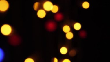 Soyut sahte arkaplan hareket halinde. Parlak, bulanık renkli parçacıklar, ışıklar. Koyu arkaplandaki çelenklerden parlak bir bokeh. Yeni yıl ya da Noel arkaplanı.