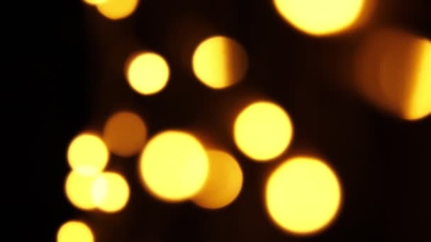 Abstrakter Bokeh-Hintergrund in Bewegung. glänzende, verschwommene Goldpartikel, Lichter. helles Bokeh aus Girlanden auf dunklem Hintergrund. Neujahr oder Weihnachten festliche Kulisse. — Stockvideo