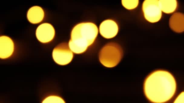 Resumen bokeh fondo en movimiento. partículas doradas brillantes y borrosas, luces. brillante bokeh de guirnaldas sobre fondo oscuro. Año nuevo o Navidad de fondo festivo. — Vídeo de stock