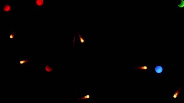 黒の背景に多色のガーランドライト。新年やクリスマス、多彩なお祝いや魔法の背景. — ストック動画