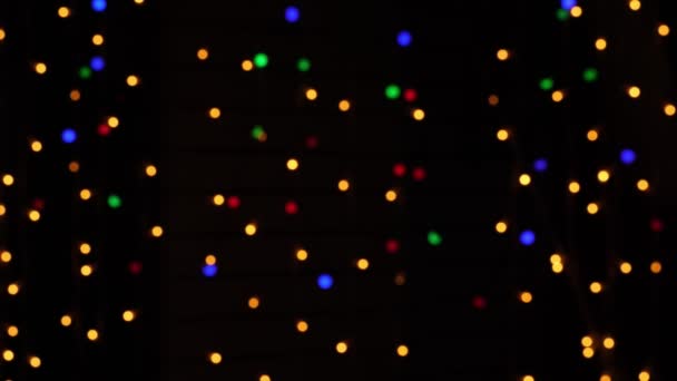 Abstrakter Bokeh-Hintergrund in Bewegung. leuchtende, verschwommene bunte Teilchen, Lichter. helles Bokeh aus Girlanden auf dunklem Hintergrund. Neujahr oder Weihnachten festliche Kulisse. — Stockvideo