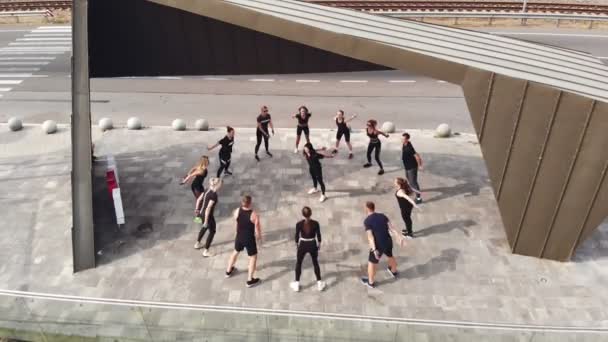 CHERKASSY, UKRAINE, 24 WRZESIEŃ 2020: grupowy trening fitness na świeżym powietrzu. Młodzi sportowcy uprawiają sport na tarasie widokowym na tamie z panoramicznym widokiem. klub sportowy. Zdjęcia lotnicze. Zdrowie — Wideo stockowe