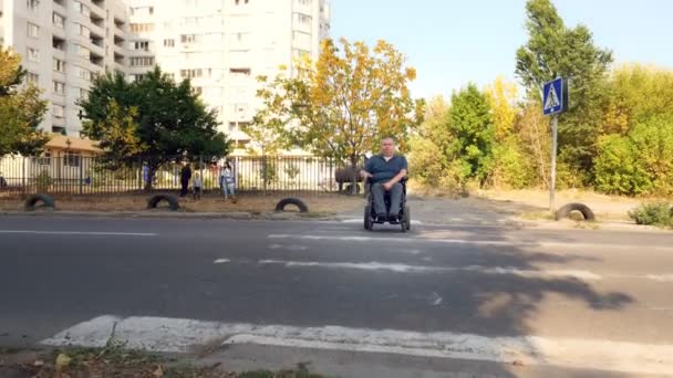 Wheelchair man. Handicapped man. a young disabled man on an automated wheelchair crosses the road at a pedestrian crossing. — Stock Video