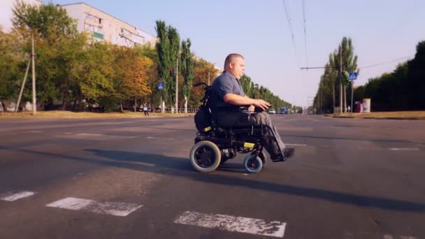 Wheelchair man. Handicapped man. a young disabled man on an automated wheelchair crosses the road at a pedestrian crossing. — Stock Video