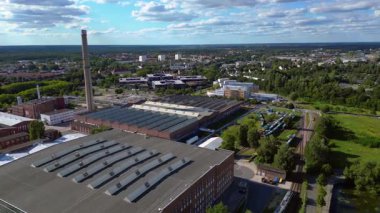 Endüstriyel binaların havadan görünüşü ve Almanya 'nın Hennigsdorf şehrinde bir bacanın yanından geçen bir tren. Hız rampası hiper hareket zaman aşımı ters uçan İHA 