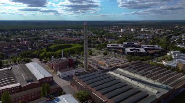 Endüstriyel binaların havadan görünüşü ve Almanya 'nın Hennigsdorf şehrinde bir bacanın yanından geçen bir tren. İHA 'nın üzerinden ters uçuş yap 