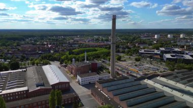Endüstriyel binaların havadan görünüşü ve Almanya 'nın Hennigsdorf şehrinde bir bacanın yanından geçen bir tren. durağan tripod havada süzülen panorama drone 