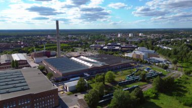 Endüstriyel binaların havadan görünüşü ve Almanya 'nın Hennigsdorf şehrinde bir bacanın yanından geçen bir tren. statik üç ayaklı insansız hava aracı 
