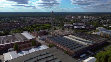 Endüstriyel binaların havadan görünüşü ve Almanya 'nın Hennigsdorf şehrinde bir bacanın yanından geçen bir tren. İHA alçalıyor 