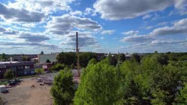 Endüstriyel binaların havadan görünüşü ve Almanya 'nın Hennigsdorf şehrinde bir bacanın yanından geçen bir tren. İHA yükseliyor 