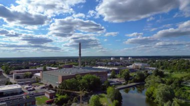 Endüstriyel binaların havadan görünüşü ve Almanya 'nın Hennigsdorf şehrinde bir bacanın yanından geçen bir tren. İHA yükseliyor 