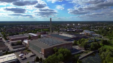 Endüstriyel binaların havadan görünüşü ve Almanya 'nın Hennigsdorf şehrinde bir bacanın yanından geçen bir tren. İHA alçalıyor 