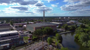 Endüstriyel binaların havadan görünüşü ve Almanya 'nın Hennigsdorf şehrinde bir bacanın yanından geçen bir tren. İHA alçalıyor 