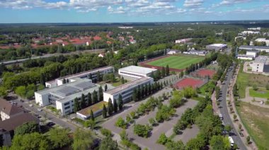 Hennigsdorf Lisesi 'ndeki spor tesisleri arasında futbol sahası, koşu pisti ve yerleşim alanlarındaki diğer binalar da var. panorama yörünge dronu 