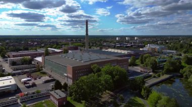 Endüstriyel binaların havadan görünüşü ve Almanya 'nın Hennigsdorf şehrinde bir bacanın yanından geçen bir tren. uçuş üstü insansız hava aracı 