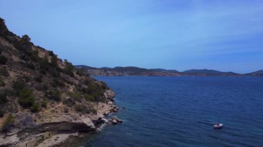 Ibiza, İspanya 'da yemyeşil bitki örtüsü olan kayalık bir sahilin yakınındaki teknelerin hava manzarası. İHA alçalıyor 