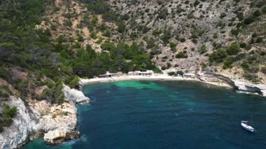 Yazın İspanya 'nın İbiza kentindeki güzel Cala Llentrisca sahilinin turkuaz suyu ve Barques de Pescadors Huts manzarası. Hız rampası hiper hareket zamanı hızlandırılmış panorama yörünge dronu 