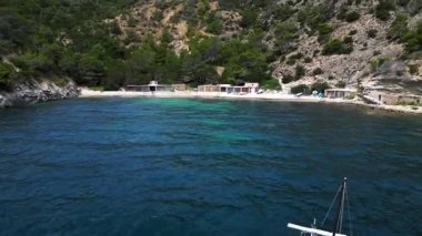 Ibiza 'da bazı balıkçıların evlerinin olduğu gizli bir sahil koyunun yakınında sakin mavi sularda yüzen yelkenli. Ters İHA hız rampasında uç. Hiper hareket süresi doluyor. 