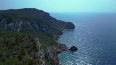 İbiza, İspanya 'da kayalık bir kayalık yüzeyi keşfeden yürüyüşçülerin hava görüntüsü. Ters İHA hız rampasında uç. Hiper hareket süresi doluyor. 