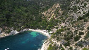 Yazın İspanya 'nın İbiza kentindeki güzel Cala Llentrisca sahilinin turkuaz suyu ve Barques de Pescadors Huts manzarası. Yukarıdan drone atışı 