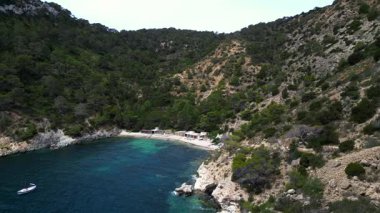 Yazın İspanya 'nın İbiza kentindeki güzel Cala Llentrisca sahilinin turkuaz suyu ve Barques de Pescadors Huts manzarası. geniş yörünge görünümü dronu 