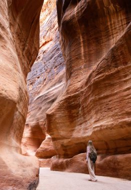 Siq 'te sırt çantalı sarışın bir kadın, Hazine El Khazneh' e giden yol, antik Petra şehri. Güney Ürdün 'deki tarihi ve arkeolojik şehir. Seyahat yerleri 
