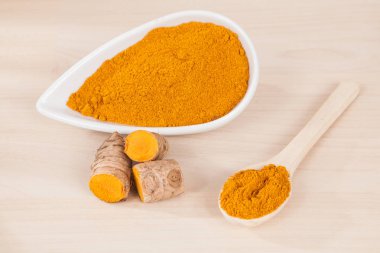 Zerdeçal tozu ve ahşap arka plan (Curcuma longa üzerinde taze zerdeçal)
