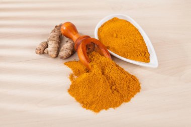 Zerdeçal tozu ve ahşap arka plan (Curcuma longa üzerinde taze zerdeçal)