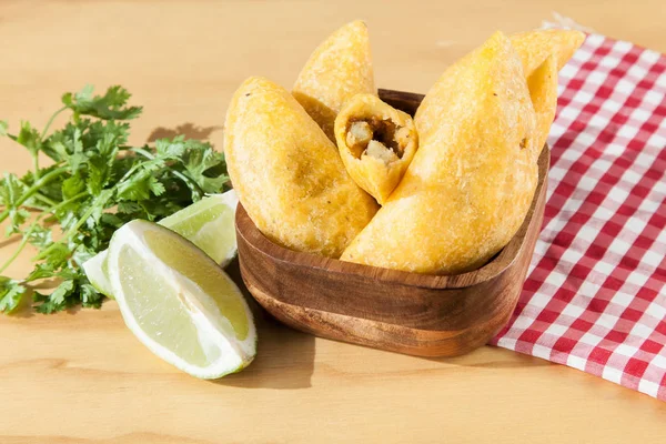 Tasty colombian food, fried empanada; photo on wooden background.