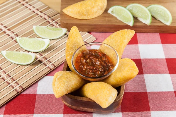 Tasty colombian food, fried empanada; photo on wooden background.