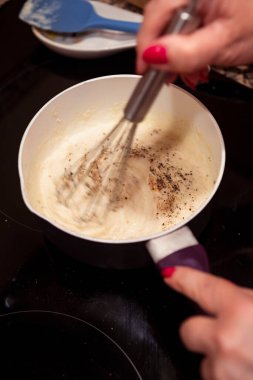 Tavada beşamel sosu çırpıyorum. İtalyan lazanyası için ev yapımı beşamel sosu bulanıklaştırılmış hareket.