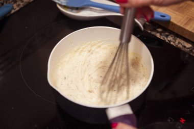 Tavada beşamel sosu çırpıyorum. İtalyan lazanyası için ev yapımı beşamel sosu bulanıklaştırılmış hareket.