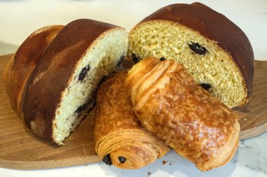 Ahşap bir tahtada altın somun ve yumuşak çikolatalı hamur işleri, zanaatkar fırın stili ve davetkar dokuma.