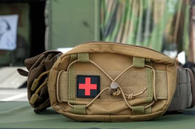 Taktik kesesinde kırmızı haç sembolü olan askeri ilk yardım çantası acil tıbbi bakım, hayatta kalma ve saha ekipmanlarını temsil ediyor..