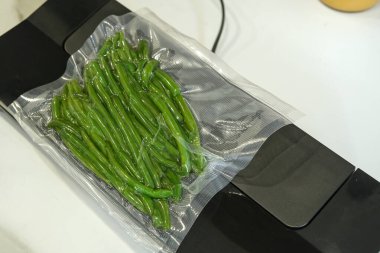 Süpürge mühürü temiz bir torbada taze taze taze fasulyeleri koruyor, yiyecek depolama ve taze tutma tekniğini gösteriyor..