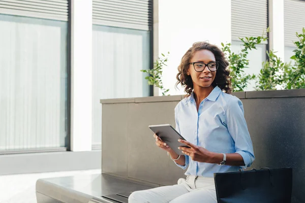 Woman sitting at office building with digital tablet in hands