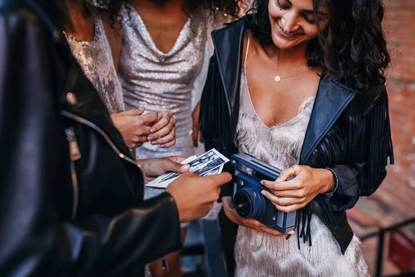 Hands of women with photographs and instant camera