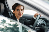 Pohled z boku na obchodnici, jak řídí auto a dívá se z okna. Portrét ženy, jak jde do kanceláře ve svém autě.