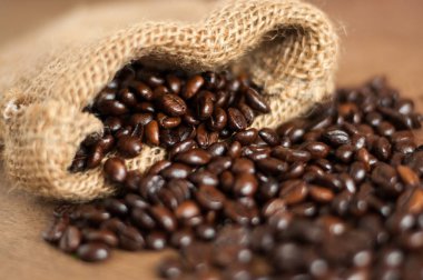 Küçük jüt çuval dışında taze kavrulmuş koyu kahve çekirdekleri, yakın