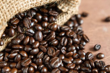 Küçük jüt çuval dışında taze kavrulmuş koyu kahve çekirdekleri, yakın