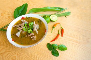 Baharatlı ördek çorbası, beyaz bardakta, tahta masada.