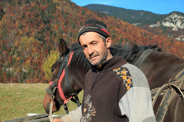 Europe, Romania, Transylvania, Carpathian Mountains, Magura, Piatra Craiului National Park. Men leading horse and wagon to cut hay.