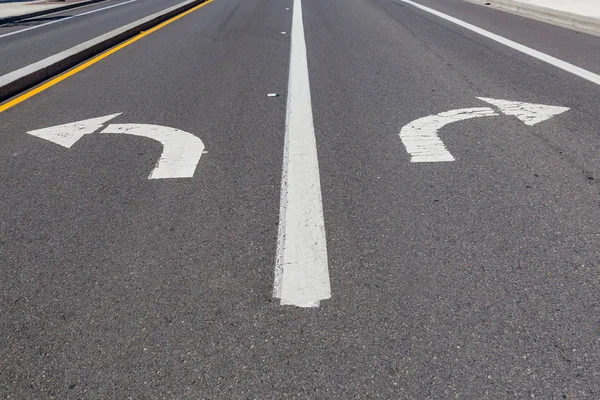 Directional arrows pointing left and right painted on a highway.