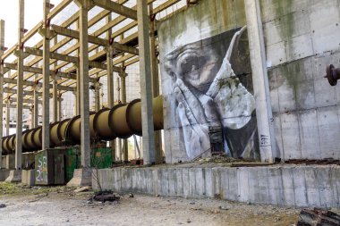 Doğu Avrupa, Ukrayna, Pripyat, Çernobil. 10 Nisan 2018. Bitmemiş soğutma kulesinin içinde, bir duvar resmi yorgun bir doktoru tasvir eder. Avustralyalı sanatçı Guido van Helton tarafından 2016 yılında Igor Kostin'in bir fotoğrafından uyarlanan bir resim. 